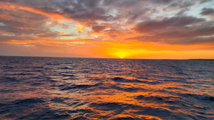 Beach sunset in Hawaii - orange and purple sky over the blue water